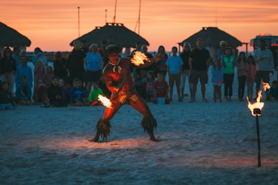 man dancing fire dance surrounded by people at beach dancer zoom background