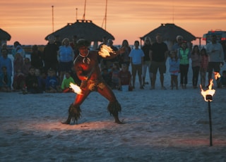 man dancing fire dance surrounded by people at beach