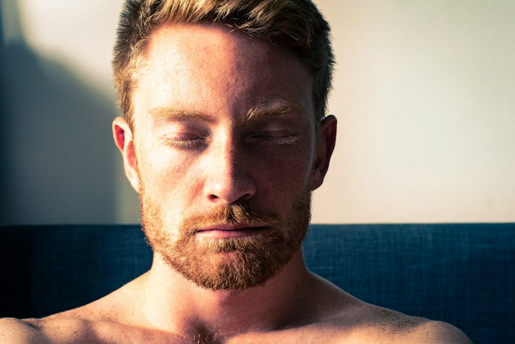 Uomo con gli occhi chiusi e il viso rilassato nella luce calda del mattino