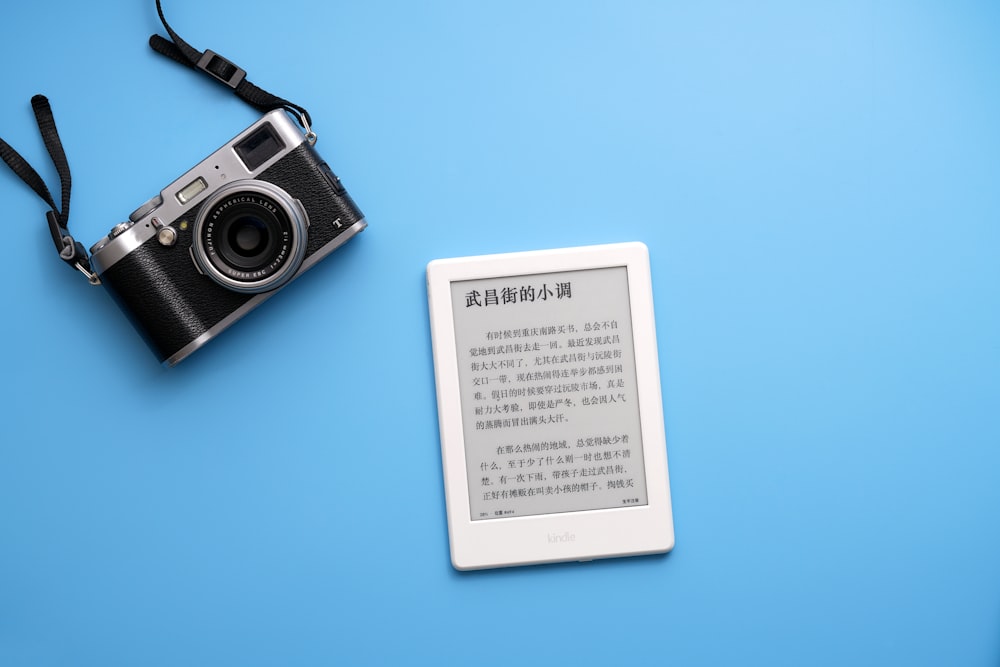 black SLR camera on and white e-book reader