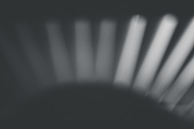 Abstract light patterns blending deep blacks and warm neutrals, evoking a calm, sensory atmosphere.