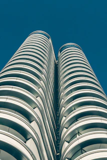 A stunning aerial view of the twin towers of BPTP Skynest piercing the sky with their sleek glass facades reflecting the sunset.