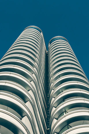 A stunning aerial view of the twin towers of BPTP Skynest piercing the sky with their sleek glass facades reflecting the sunset.