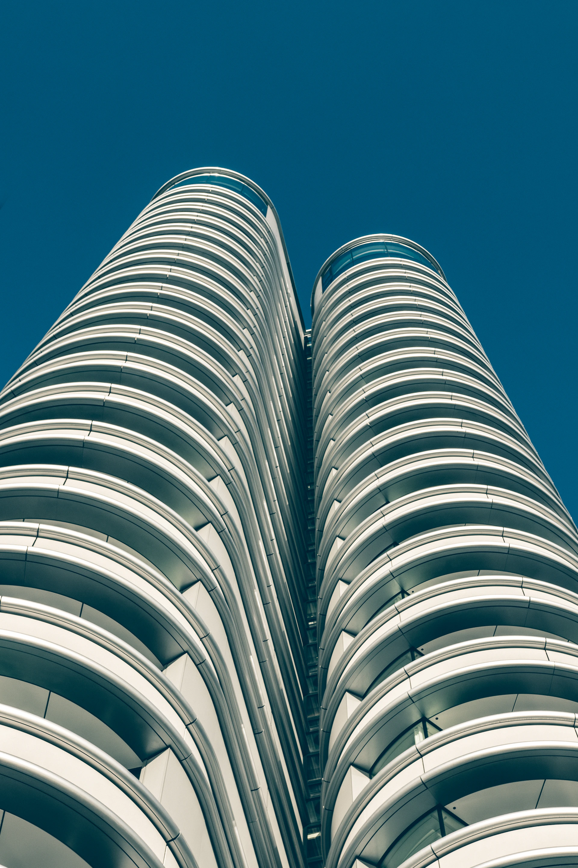 A stunning vertical shot of BPTP Skynest's twin towers piercing the sky with their sleek glass façade reflecting the soft morning light.