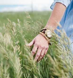 person wearing gold-colored analog watch with link bracelet