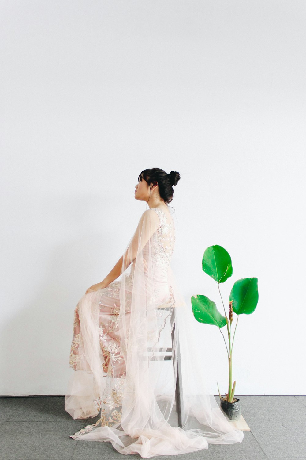 Femme assise sur un tabouret près d’une plante à feuilles