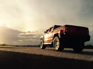 A rugged Logancrest truck driving through a sunset-lit highway surrounded by open wilderness.