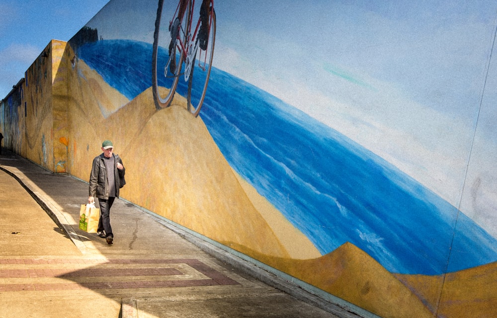 man walking along graffiti-painted wall