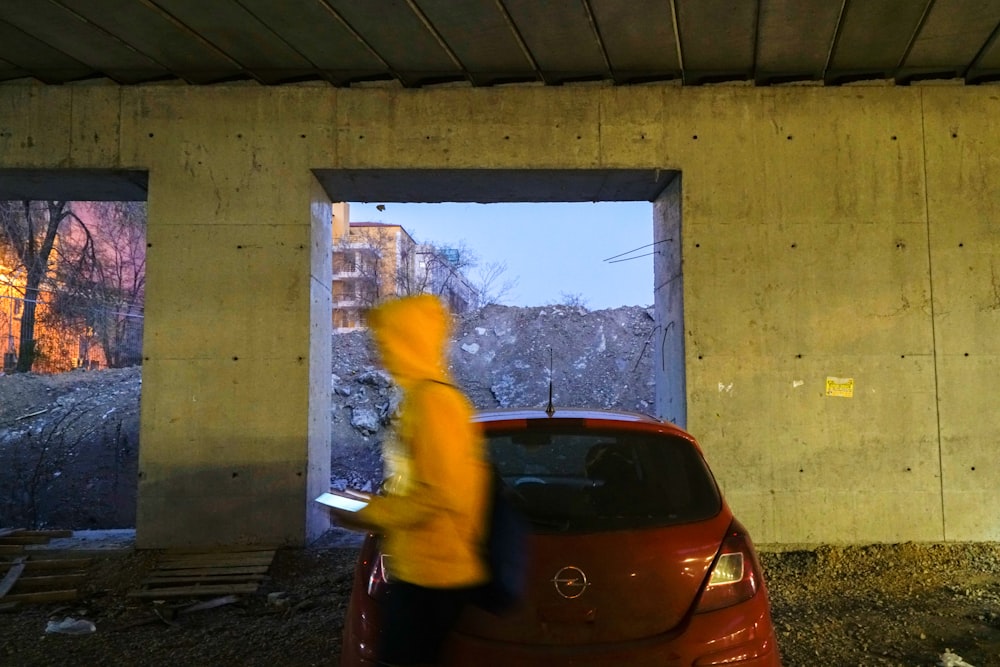person wearing yellow hoodie near red Opel car