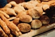 Freshly baked bread and rolls displayed on a bakery shelf