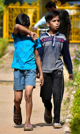 A group of boys wearing stylish casual clothes walking outdoors on a sunny day.