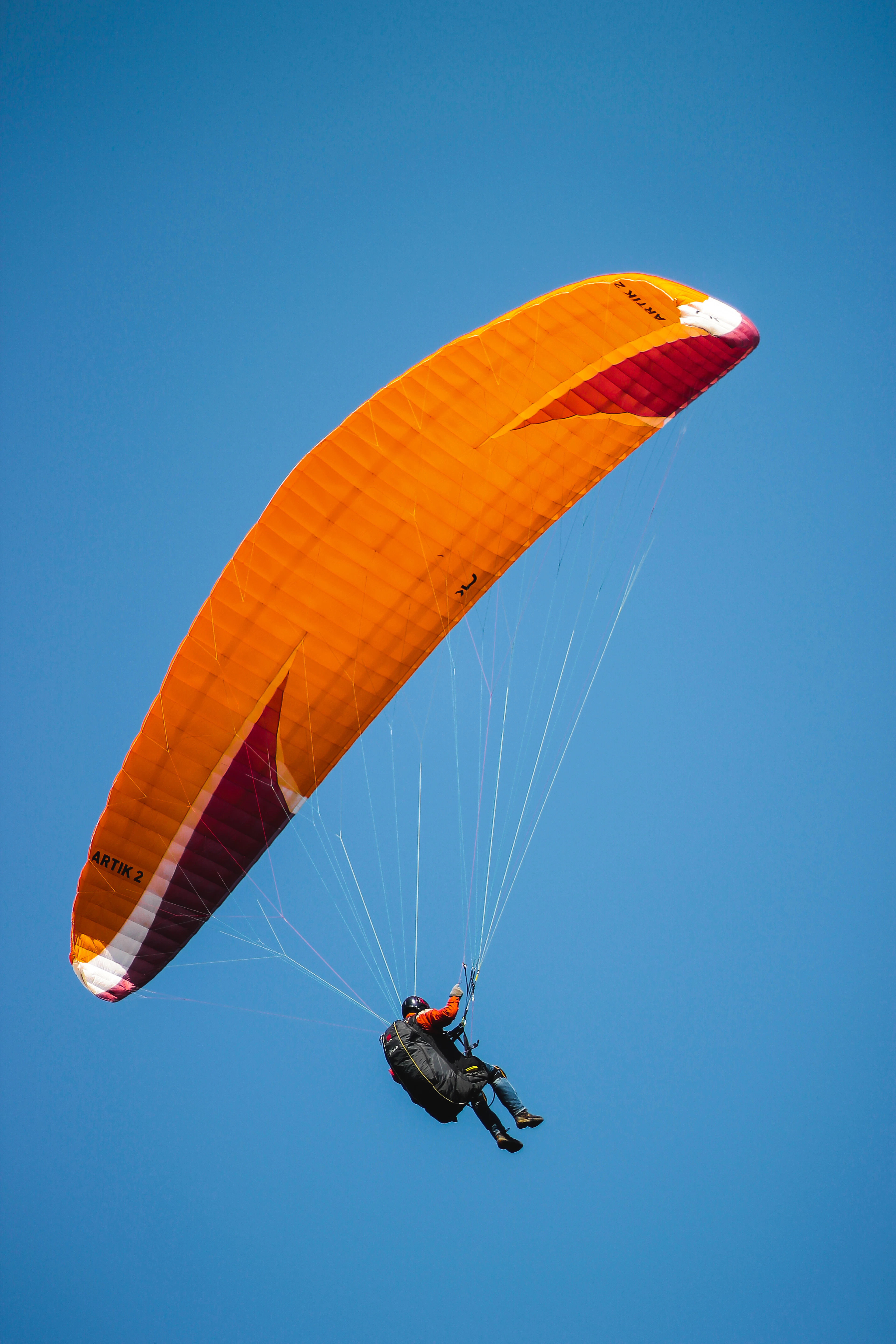 Orange paraglider wing against a blue sky