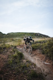 man riding mountain bike on hill under cloudy skies