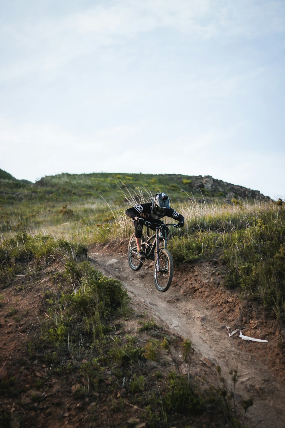 man riding mountain bike on hill under cloudy skies