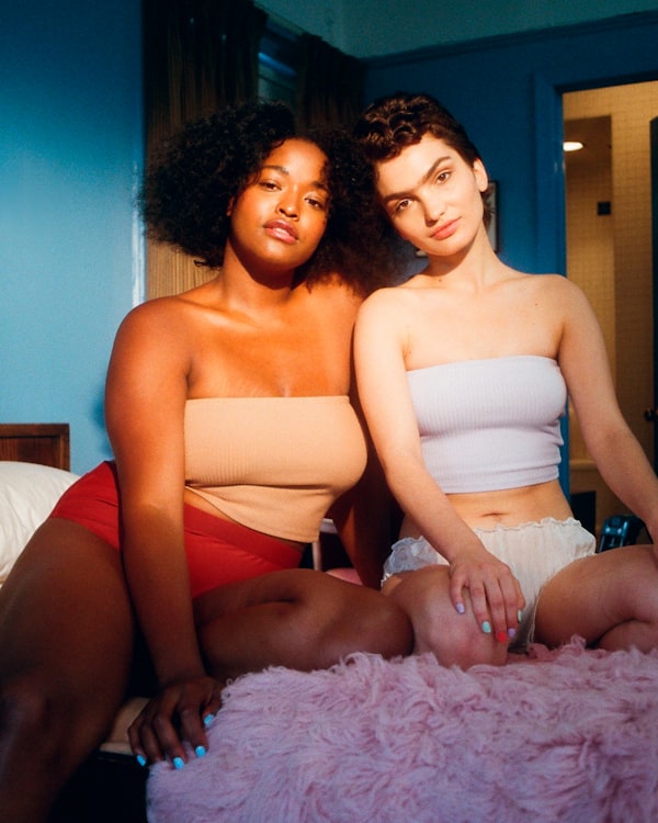 Two women of different races sitting together looking at the camera