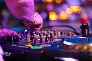 A vibrant DJ mixing music on turntables with colorful lights in the background.