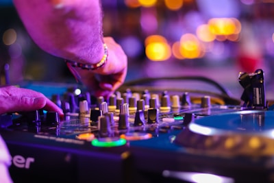 A DJ mixing tracks on turntables with vibrant city lights in the background.