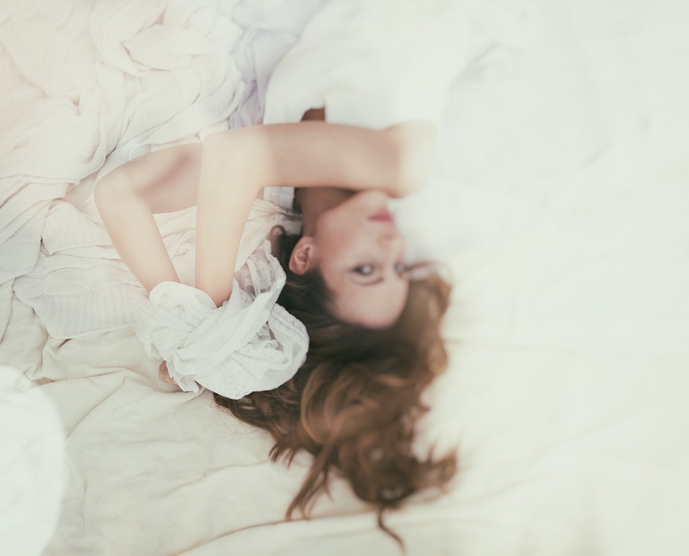 a woman laying on top of a bed under a blanket