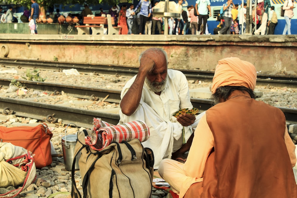 man sitting on train rail during daytime