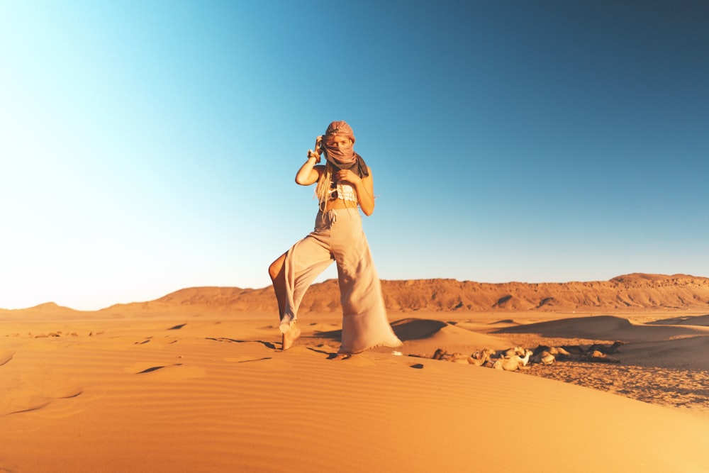 갈색 바지를 입은 여자가 사막에 서 있다