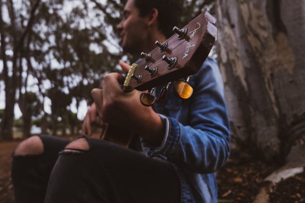 a man sitting in the woods playing a guitar