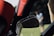 A close-up view of a set of golf clubs is prominently featured, with a blurred background showing a person playing golf on a green field. The focus is on the metal clubs with red and black head covers, while the golfer appears out of focus in the background.