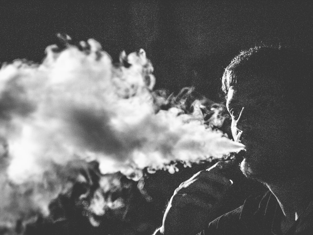 담배를 피우는 남자의 회색조 사진