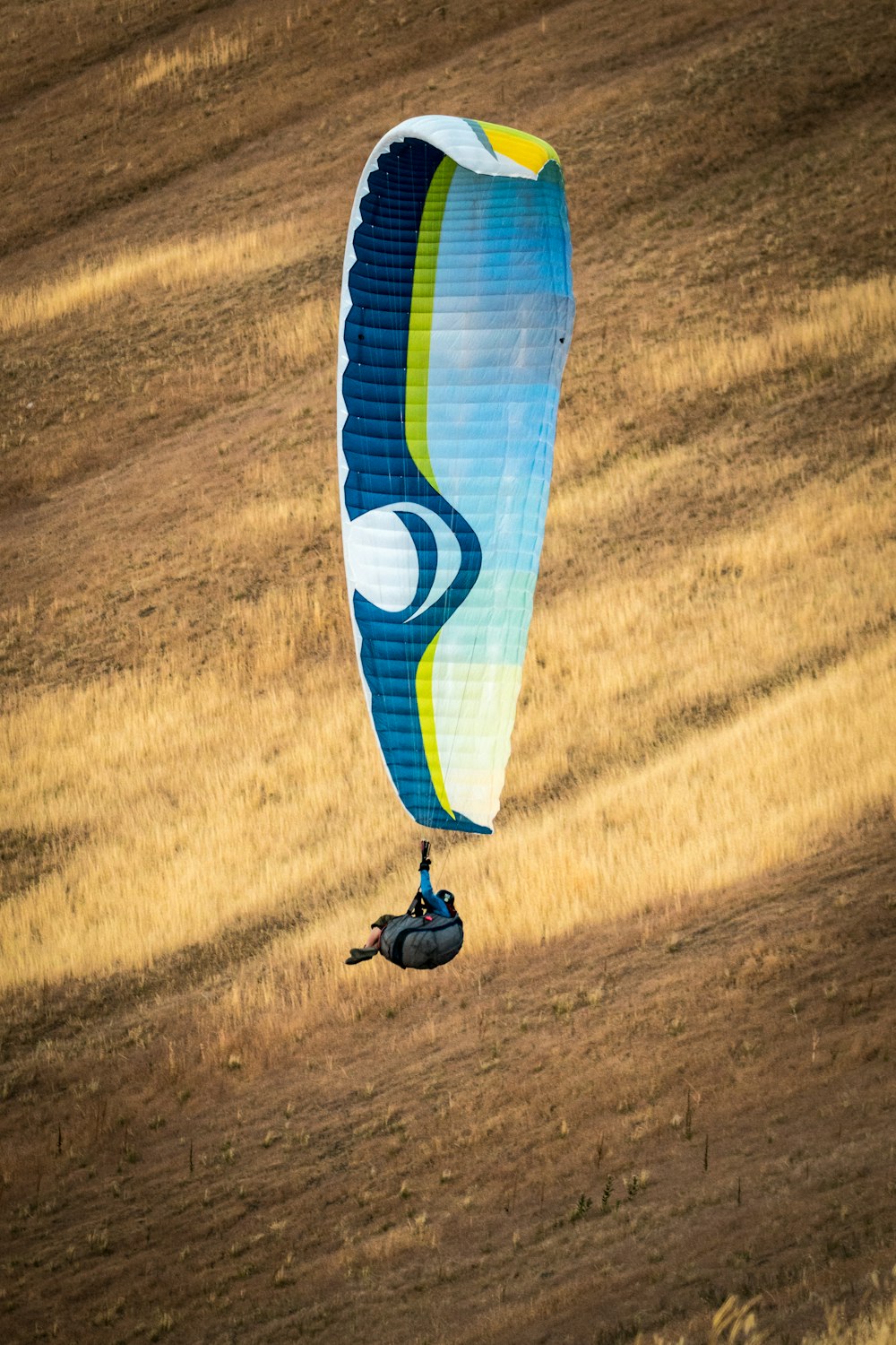 persona appesa al paracadute bianco e blu