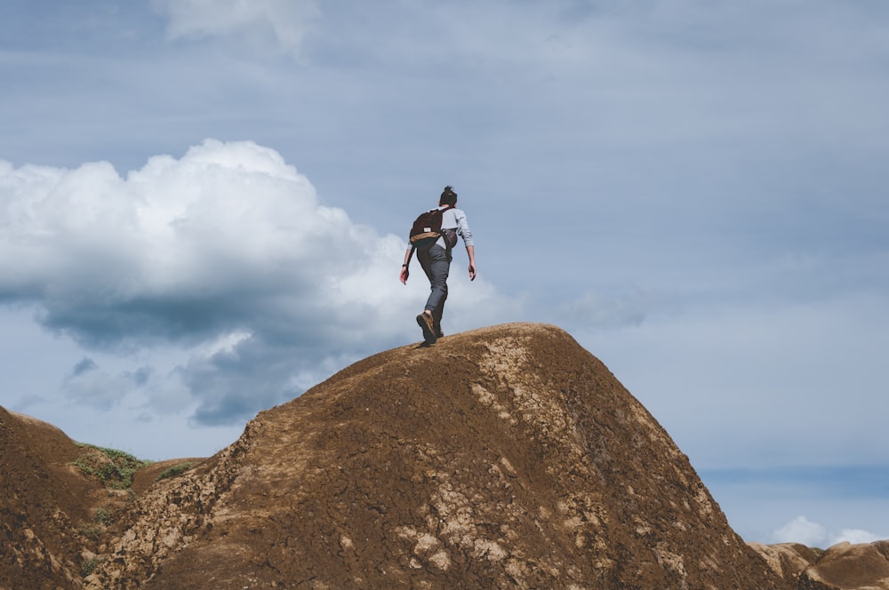 woman climbing on brown mountain during daytime