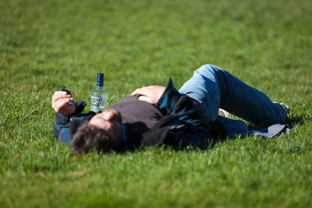 ビール瓶を持って草の中に横たわる男