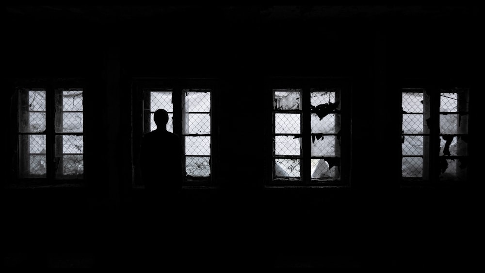 Silueta de hombre de pie cerca de la ventana