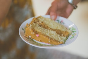 A hand holding a delicate bento cake with intricate frosting details.