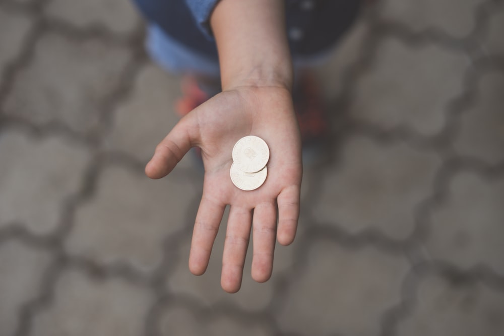 selective focus photography of person's palm with two coins