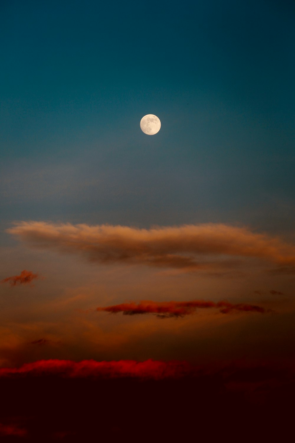 white, red, and blue sky with clouds and moon painting