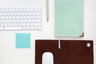 Close-up of premium office supplies including pens, notebooks, and a wireless mouse on a clean desk.
