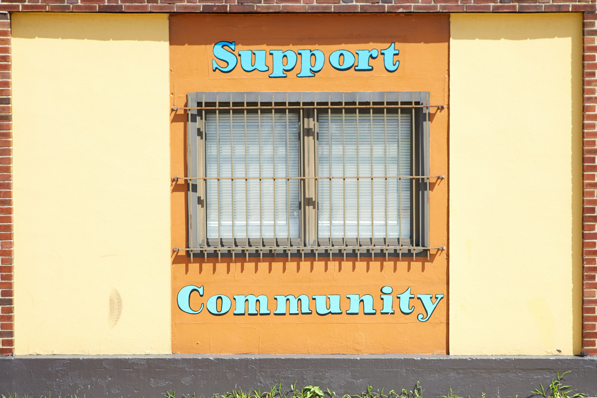 I pass by this building everyday to work.  I always thought it was a bit sad the message of ‘support’ and ‘community’ was around the steel bar window.