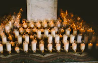Row of gently glowing candles arranged on a marble countertop.