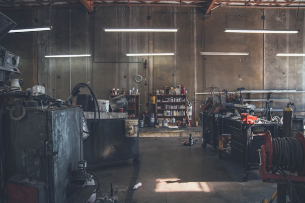 Wide angle of a dimly lit garage space featuring steel tool racks glowing under neon orange accents.