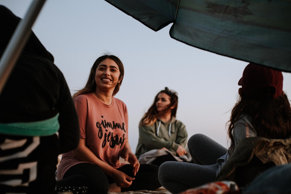 tre donne che si siedono vicino all'ombrellone del patio