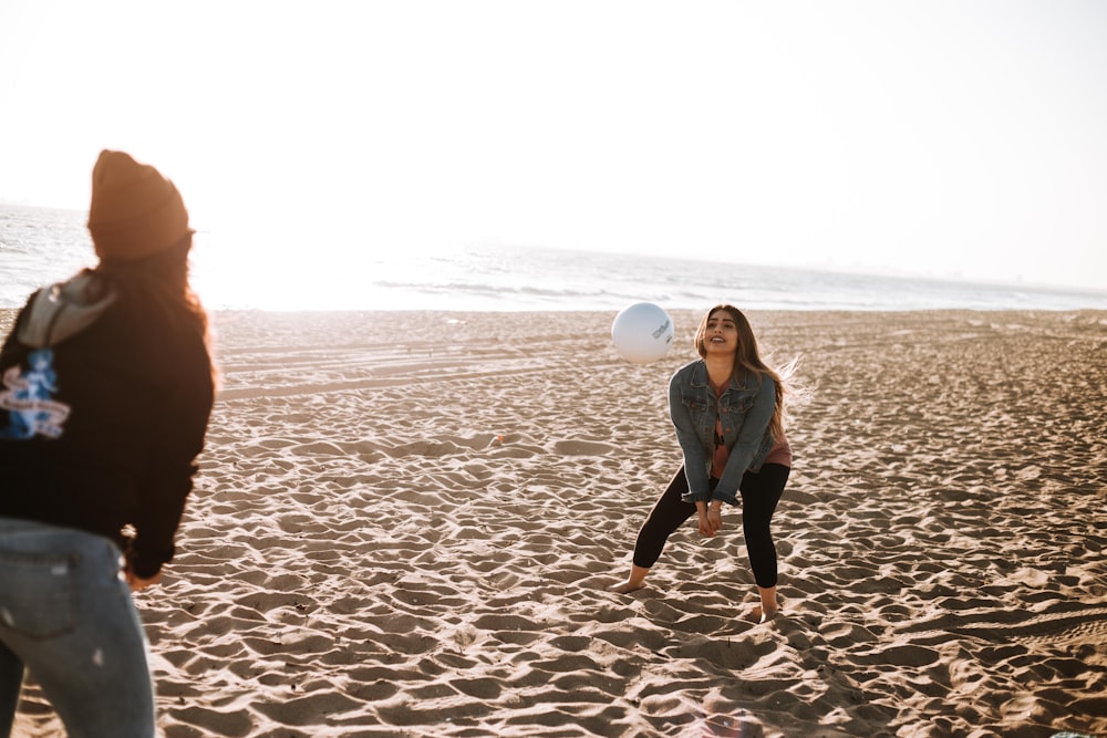 duas mulheres jogando vôlei à beira-mar