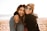 woman hugging other woman while smiling at beach