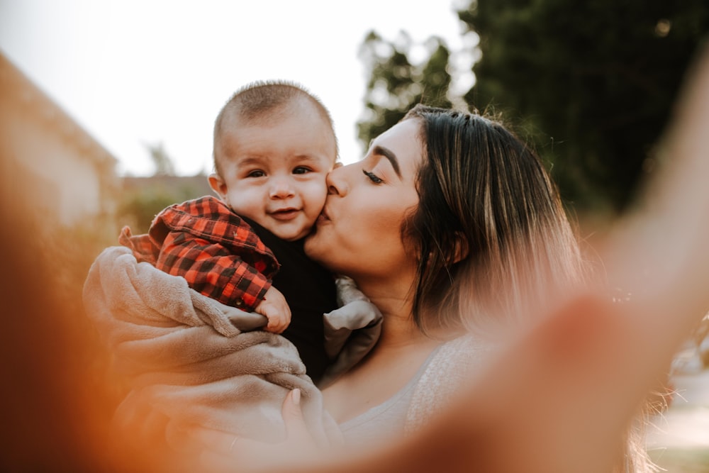 mulher beijar um bebê enquanto tira foto