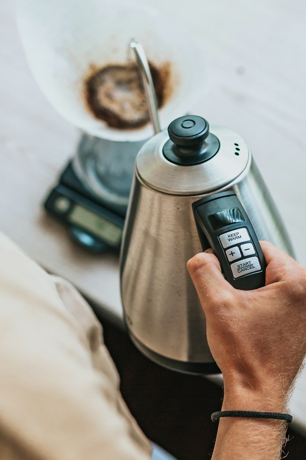 Person mit silbernem Wasserkocher aus Edelstahl