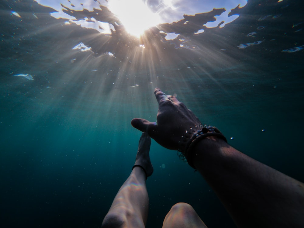 underwater photography of person soaking under sun rays