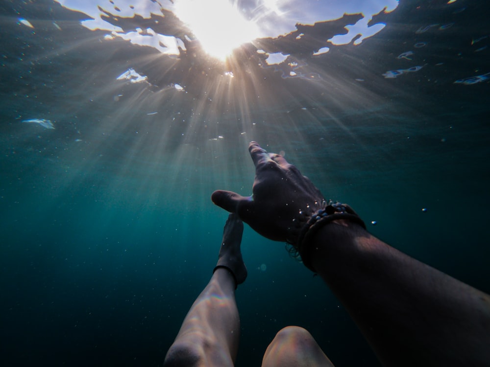 太陽の光を浴びて浸かる人の水中写真