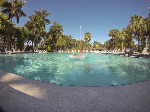 The sparkling swimming pool surrounded by comfortable lounge chairs and greenery