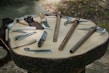 Close-up of durable, multi-use knives and compact tools laid out on a wooden surface.