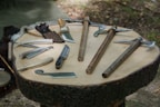 Close-up of durable, multi-use knives and compact tools laid out on a wooden surface.