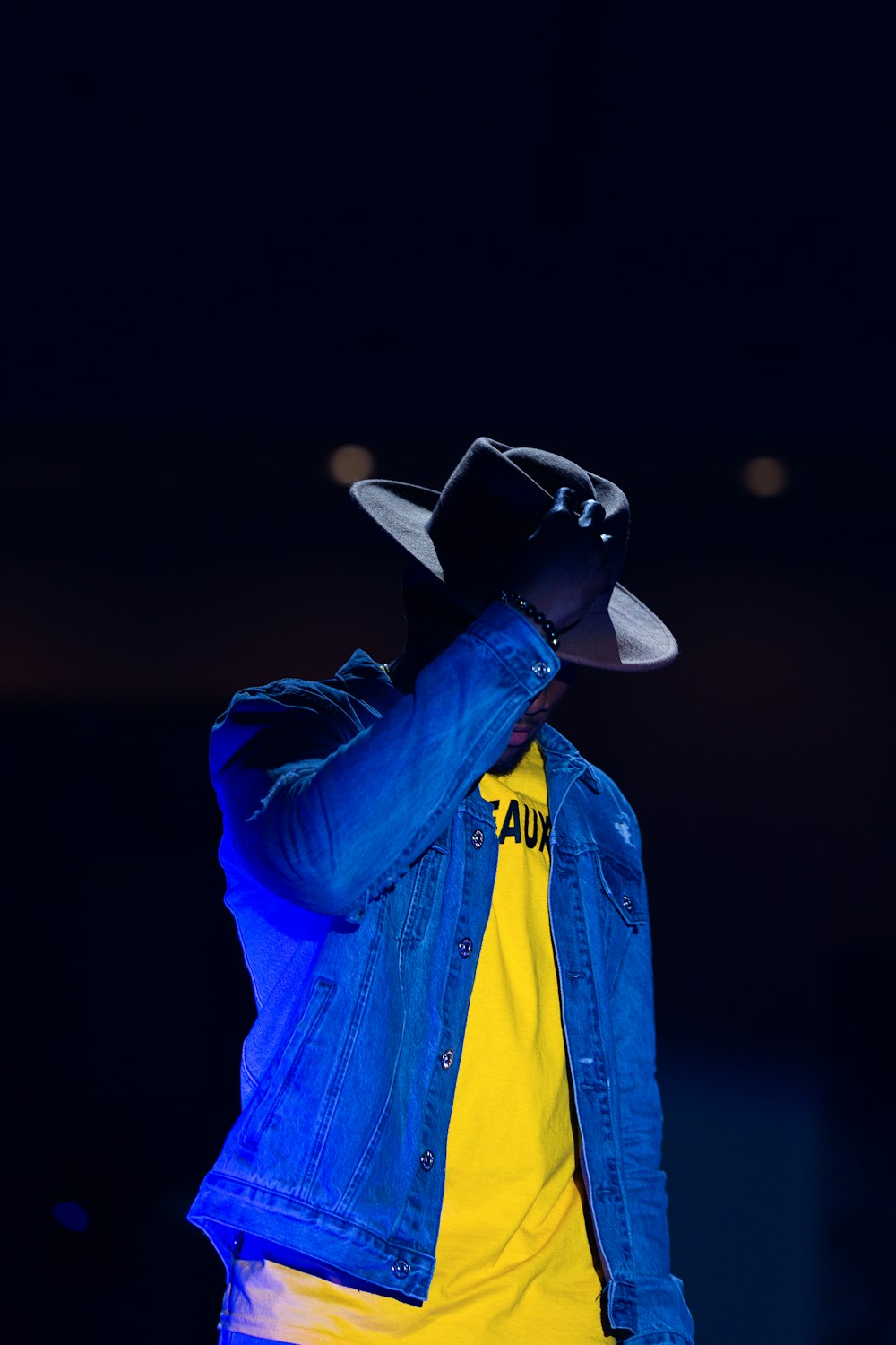 man holding on his cowboy hat on his head