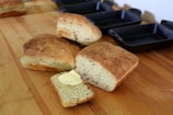 Freshly baked bread cooling on a wooden board beside a cast iron pot.